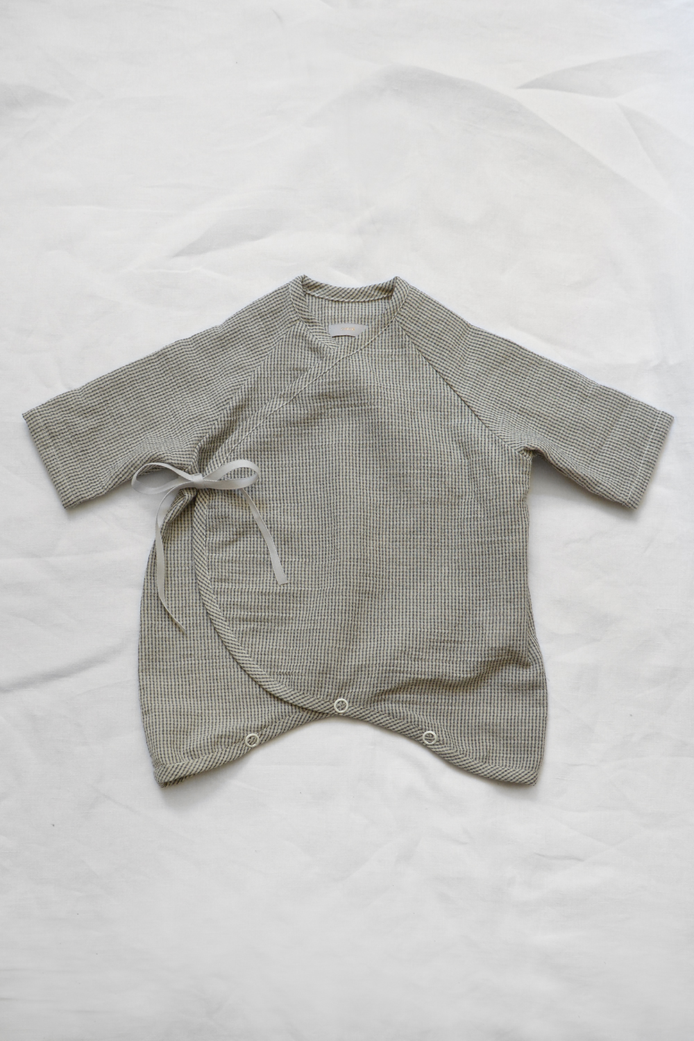 Light weight and highly breathable baby kimono onesie "Penn" in charcoal check laid flat on a white background. A GOTS certified baby clothes by Makie.