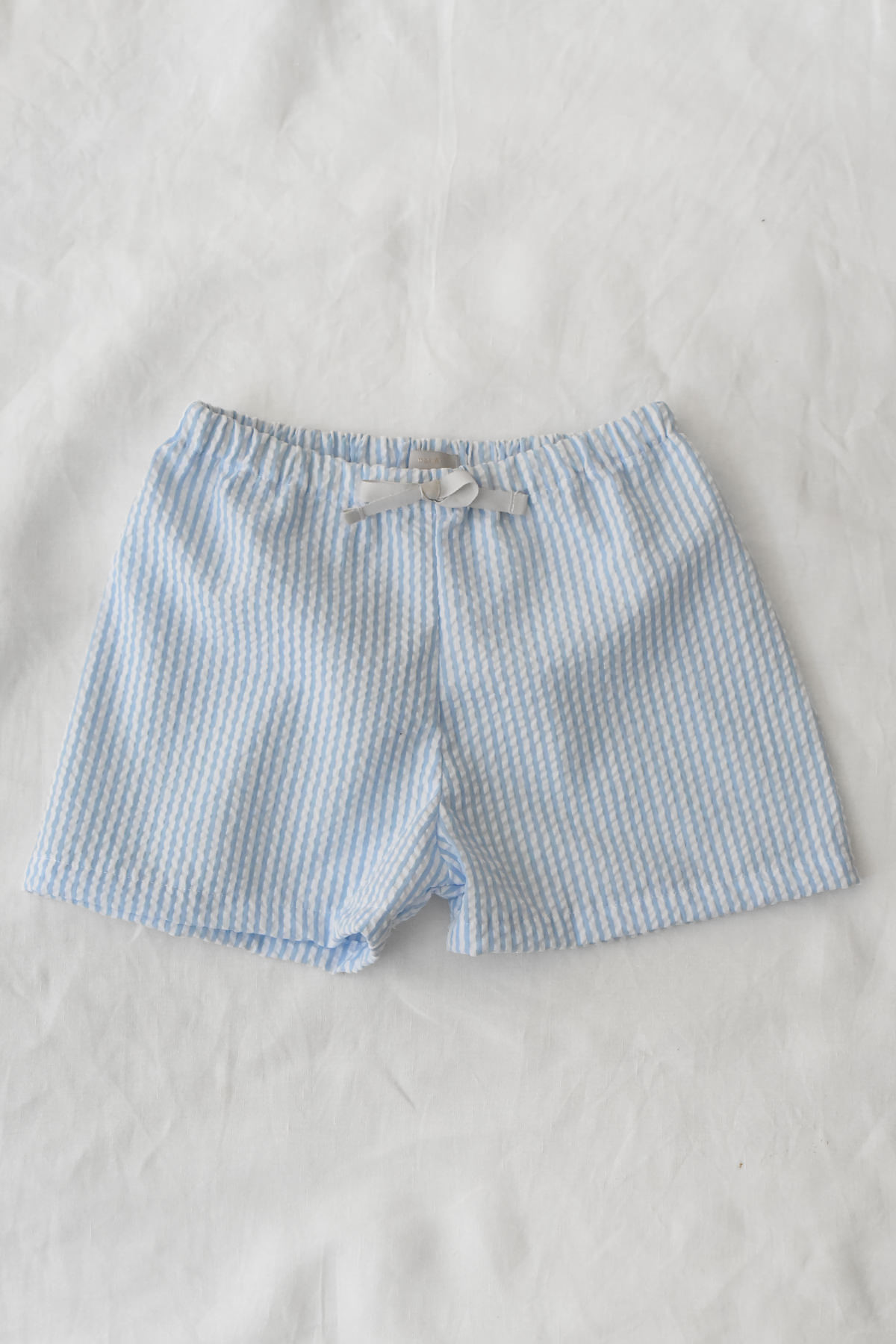 Lightweight blue and white striped shorts with elastic waistband and ribbon detail