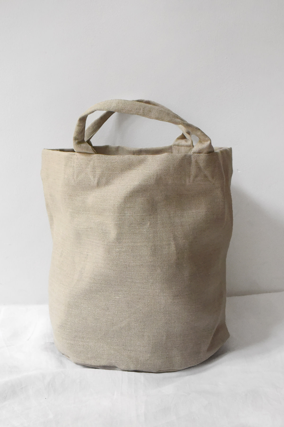 Medium-weight linen cylindrical tote bag with short handles in natural color