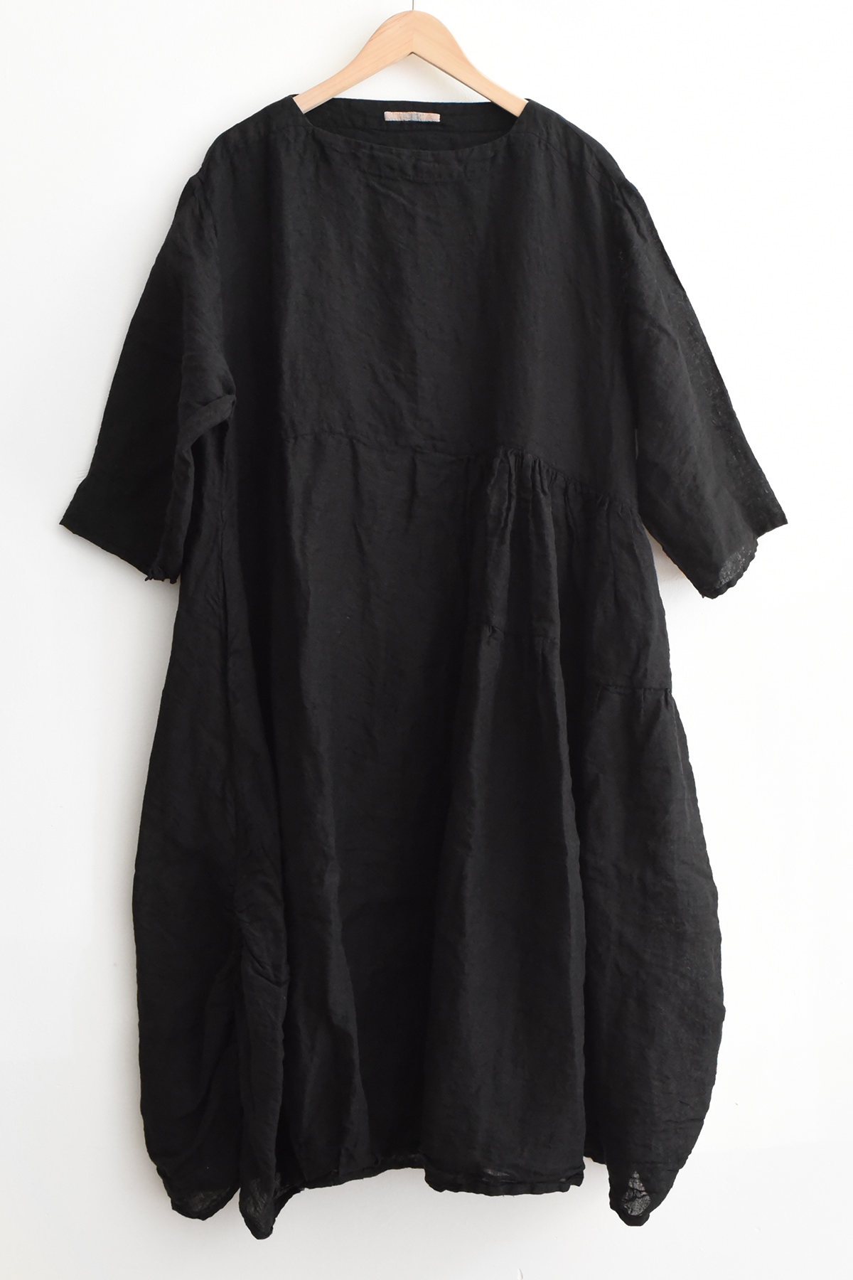 Aodress black linen dress with asymmetrical pleated panel, side pockets, smock-style hem, and relaxed sleeves