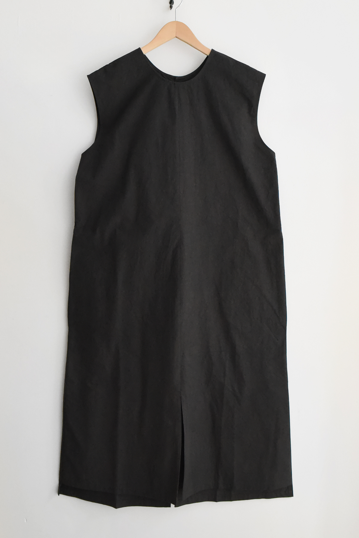 Minimal sleeveless black dress with front and back hem slits and back button closure