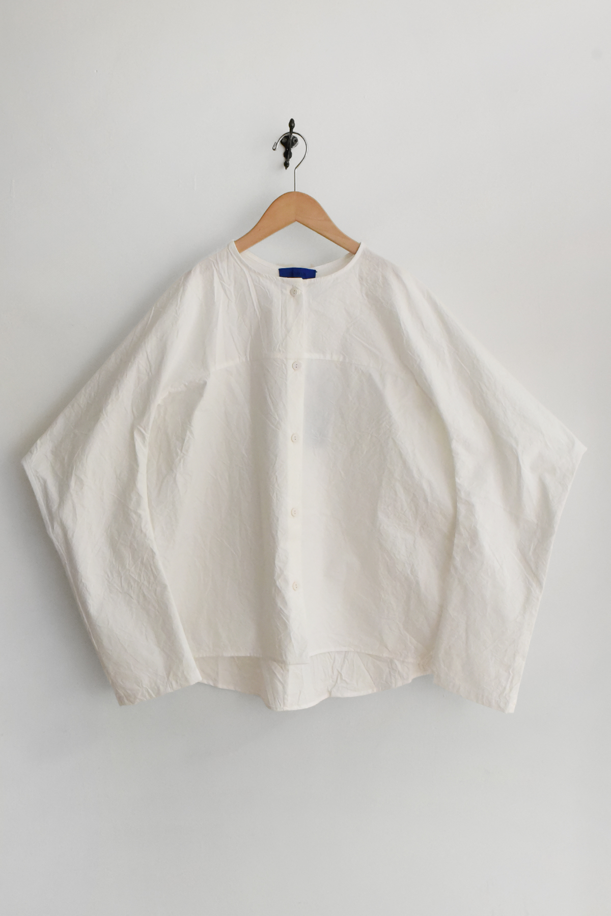 Oversized white cotton button-down shirt with cocoon sleeves and sculptural silhouette