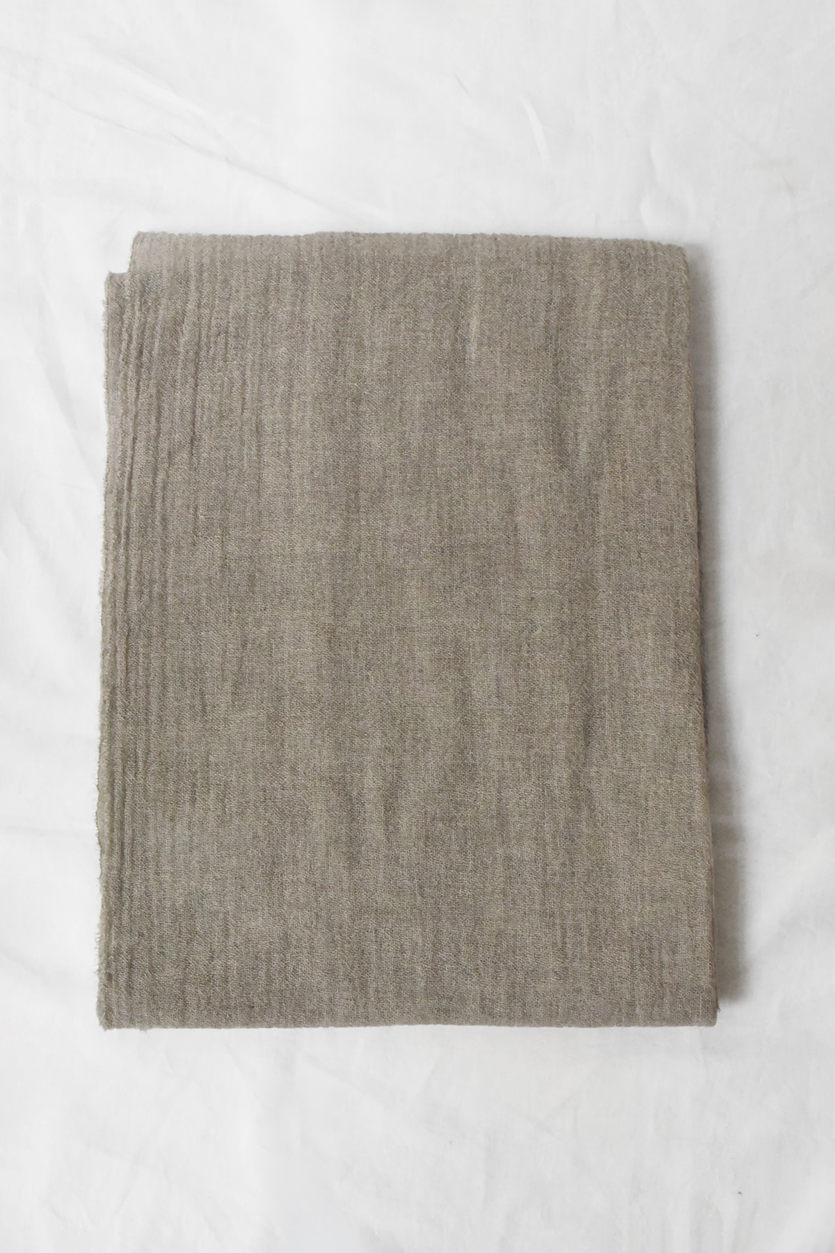 Oyuna featherweight cashmere throw in Mist folded flat, showing its airy open weave and delicate texture