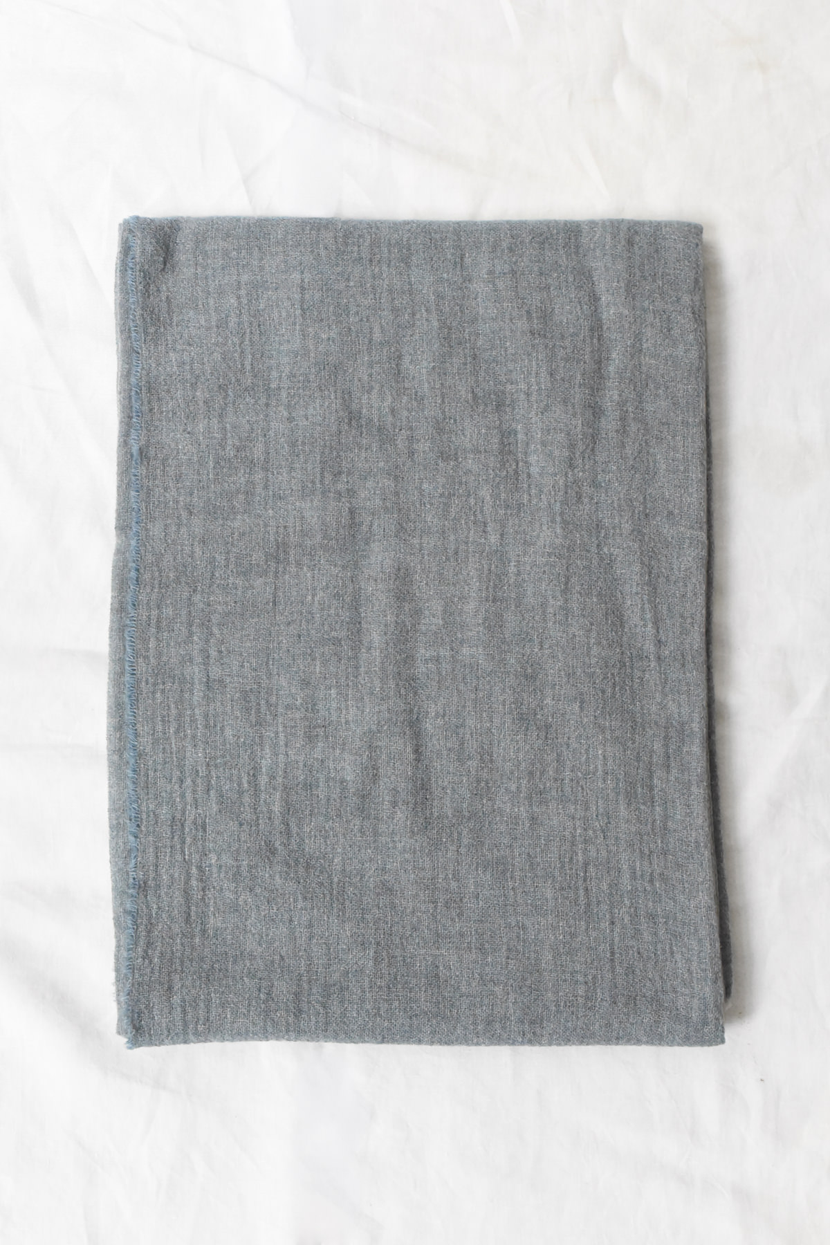 Oyuna featherweight cashmere throw in Sky folded flat, showing its airy open weave and delicate texture