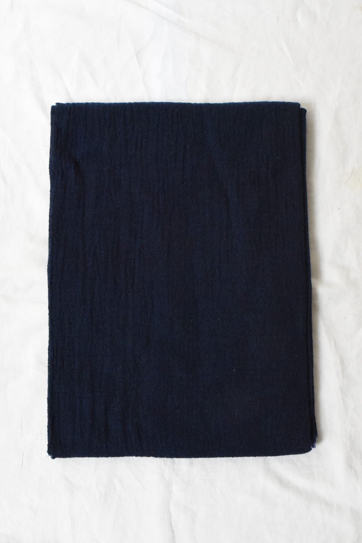 Oyuna featherweight cashmere throw in Indigo folded flat, showing its airy open weave and delicate texture