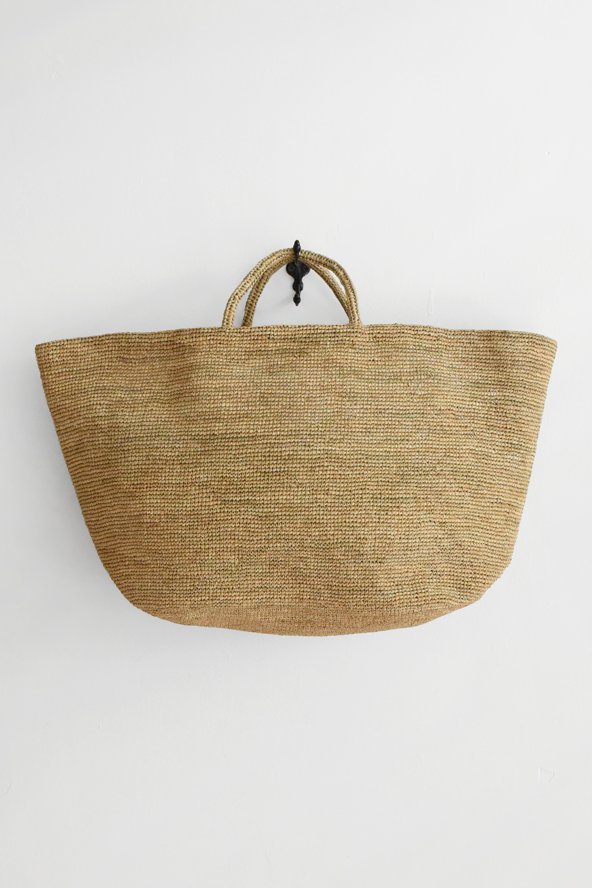 Hand crocheted natural raffia tote bag with double handles, wide rectangular shape, and tightly woven texture