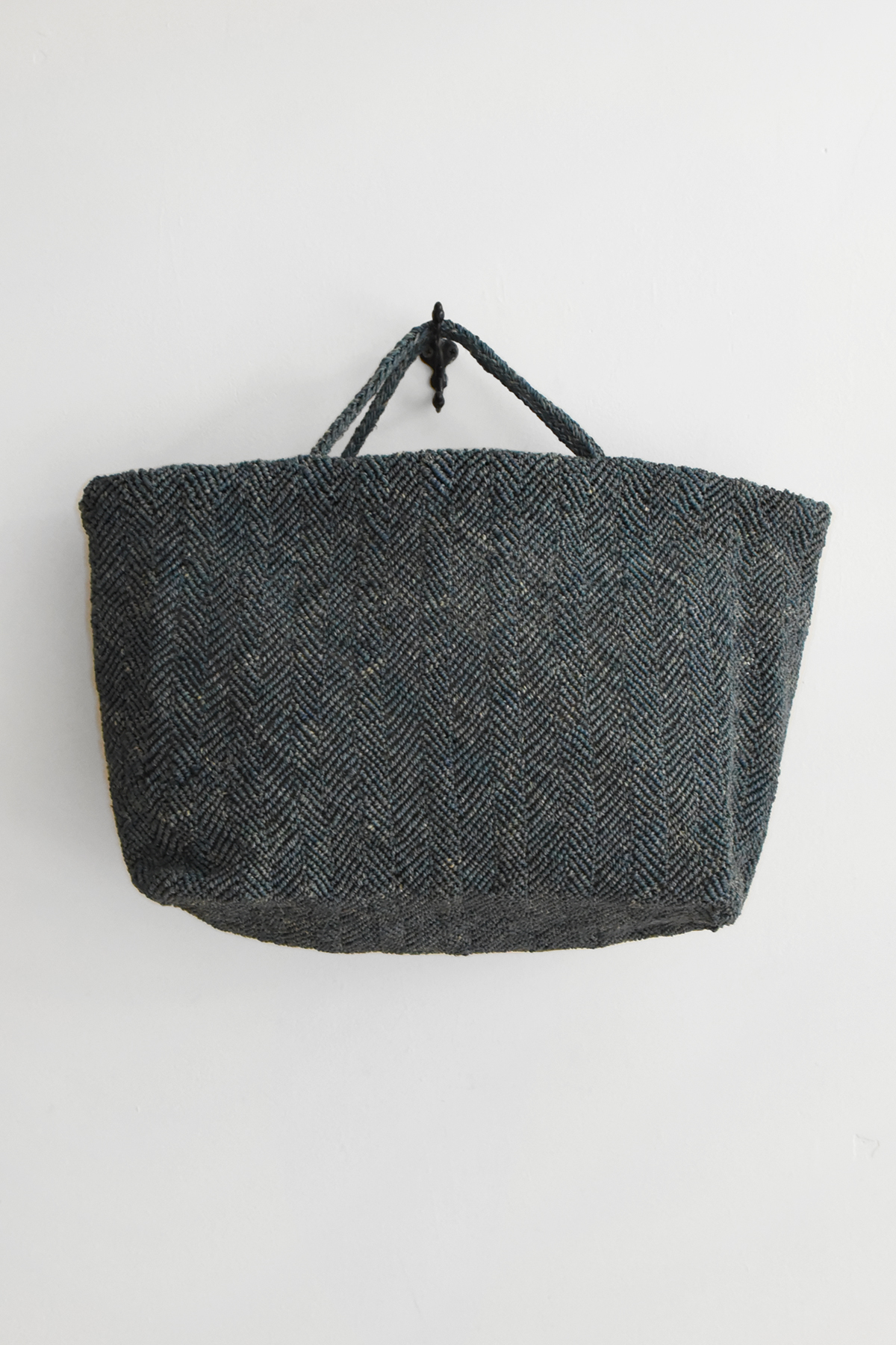 Hand crocheted raffia tote bag with chevron-like textured pattern, double handles, and wide structured shape