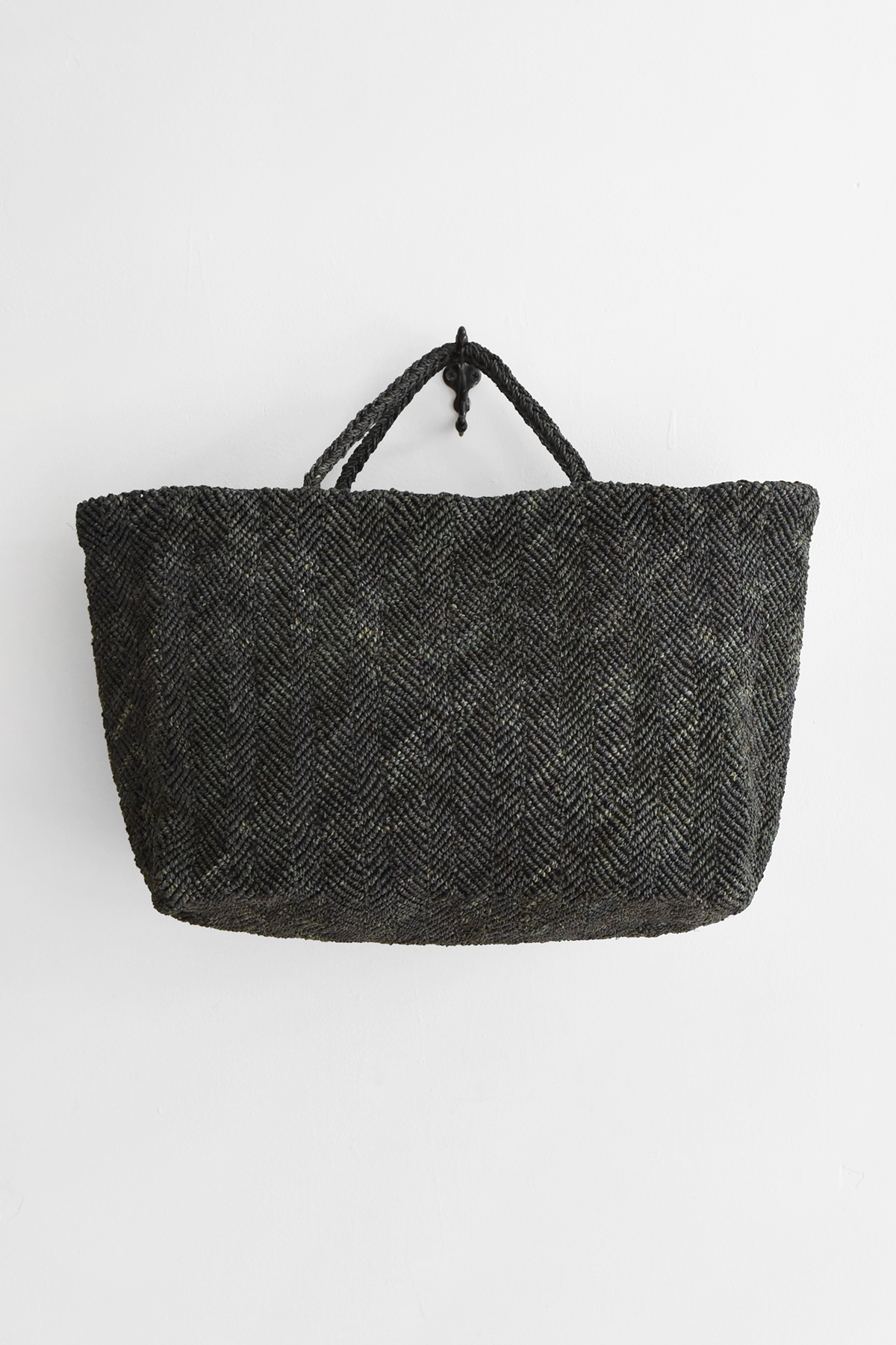 Hand crocheted raffia tote bag with chevron-like textured pattern, double handles, and wide structured shape