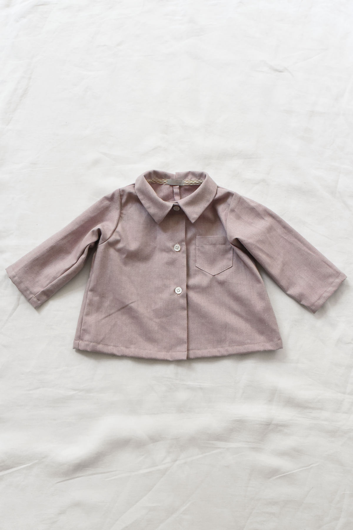 Cotton children's blouse with pointed collar and front pocket.