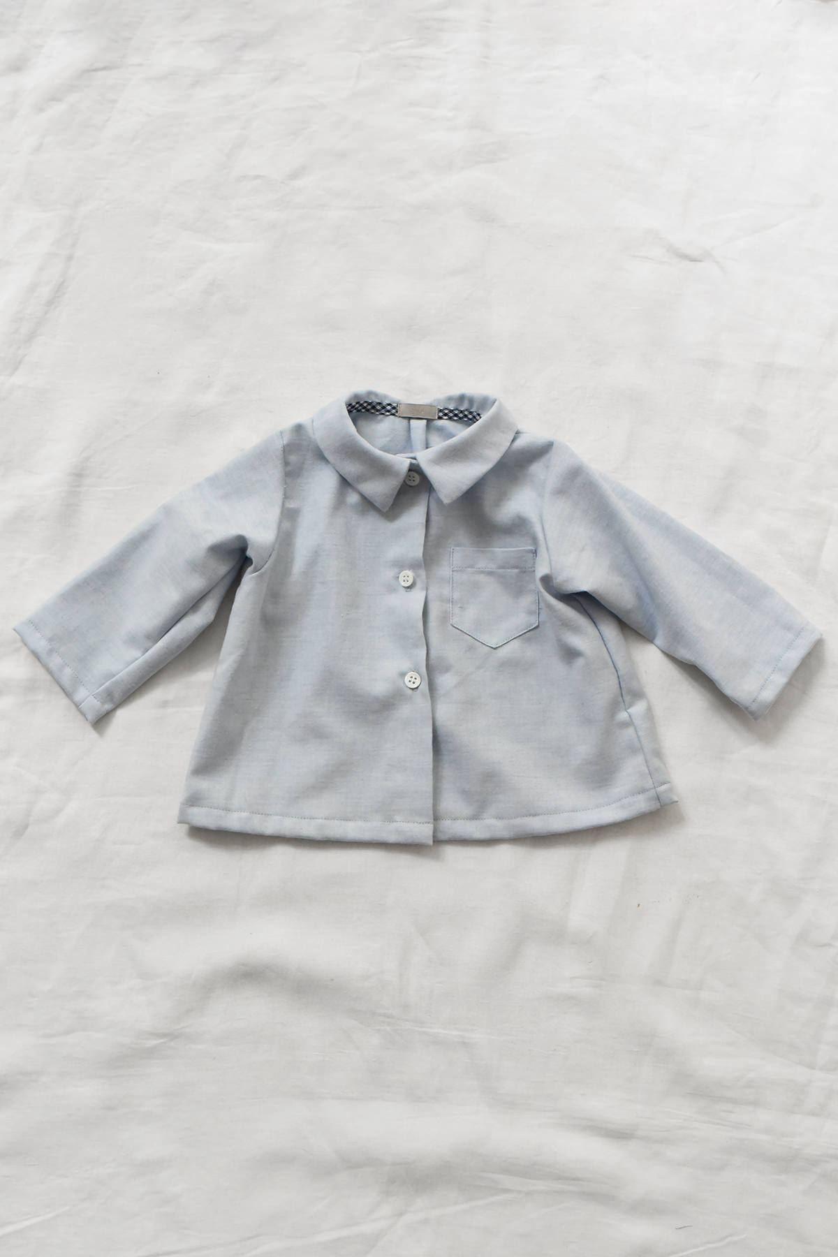 Back view of children's cotton blouse with center back pleat.