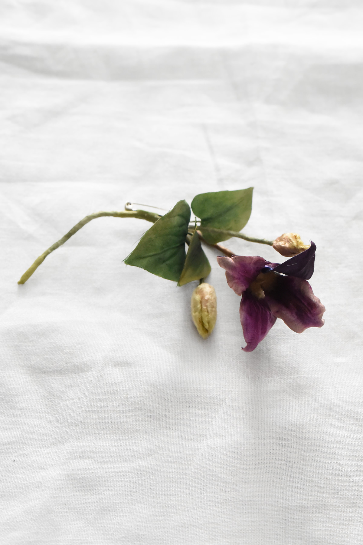 Hand-painted silk clematis artwork by Japanese artist Hitoyo featuring deep purple petals, green leaves, and detailed flower buds