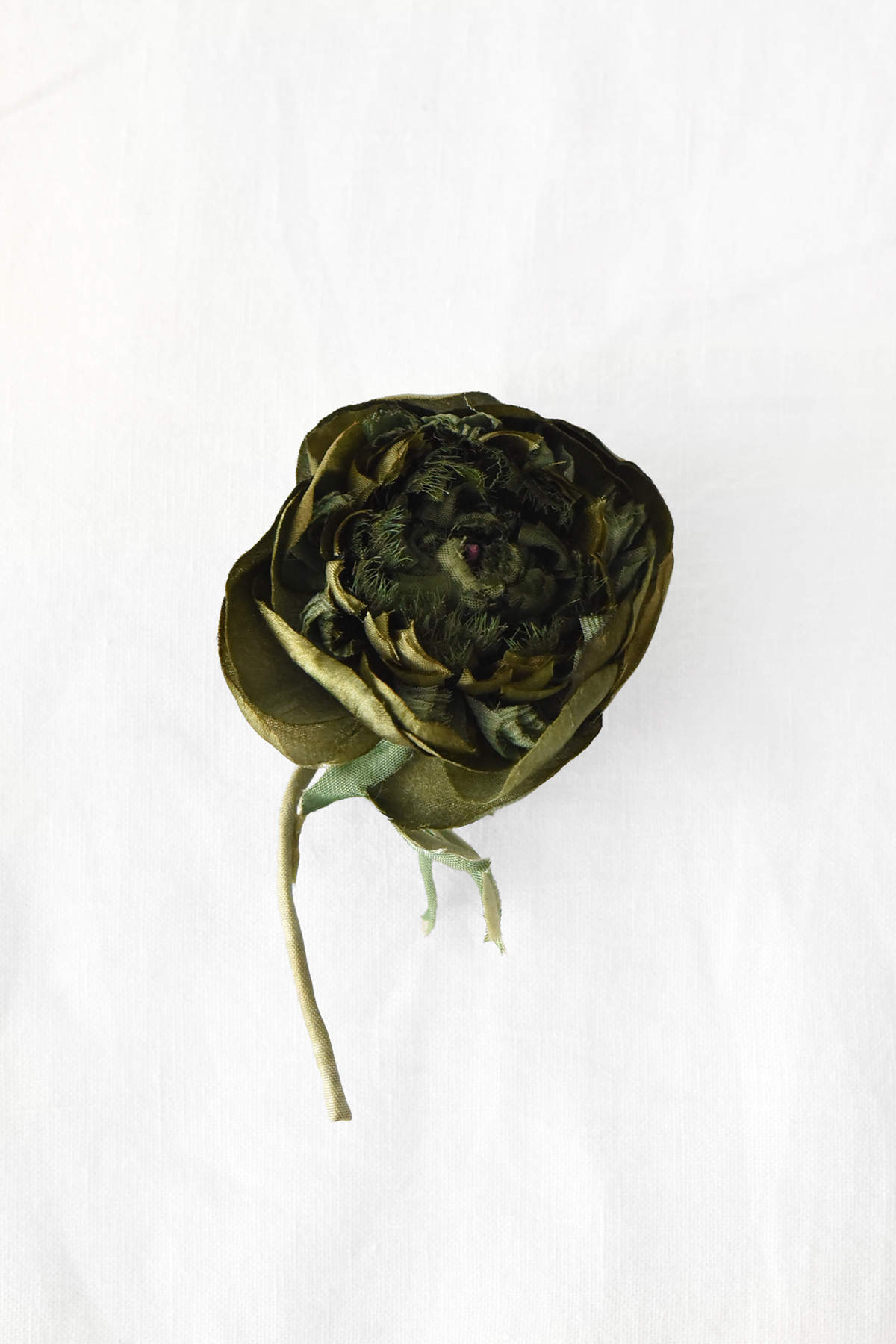 Handmade ranunculus brooch crafted from layered olive-green textile petals