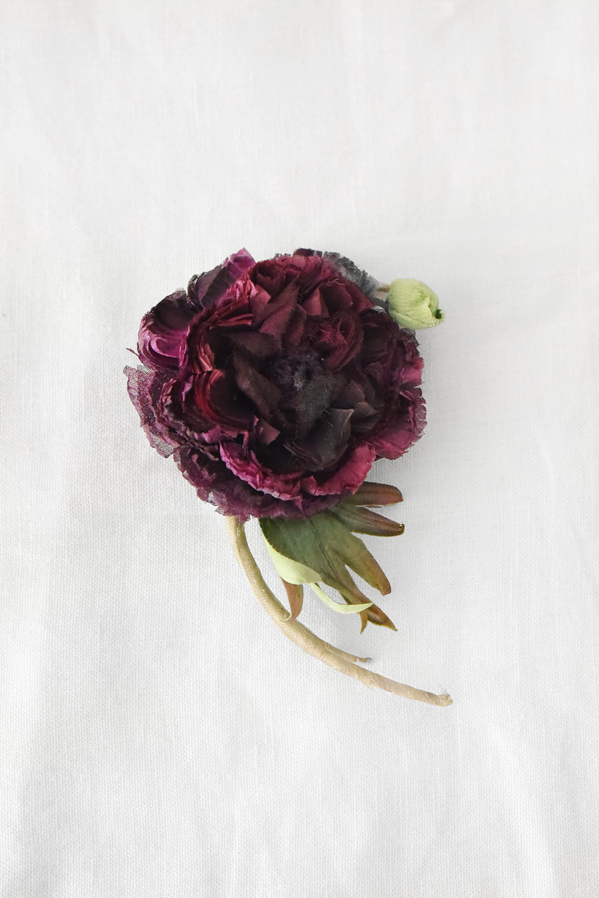 Handmade ranunculus brooch crafted from layered burgundy textile petals