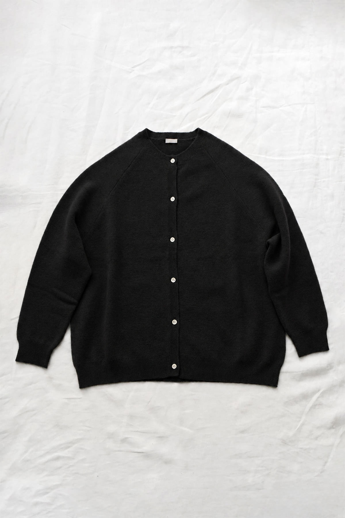 Women's black cashmere raglan cardigan with crew neck, front button closure, and ribbed trims