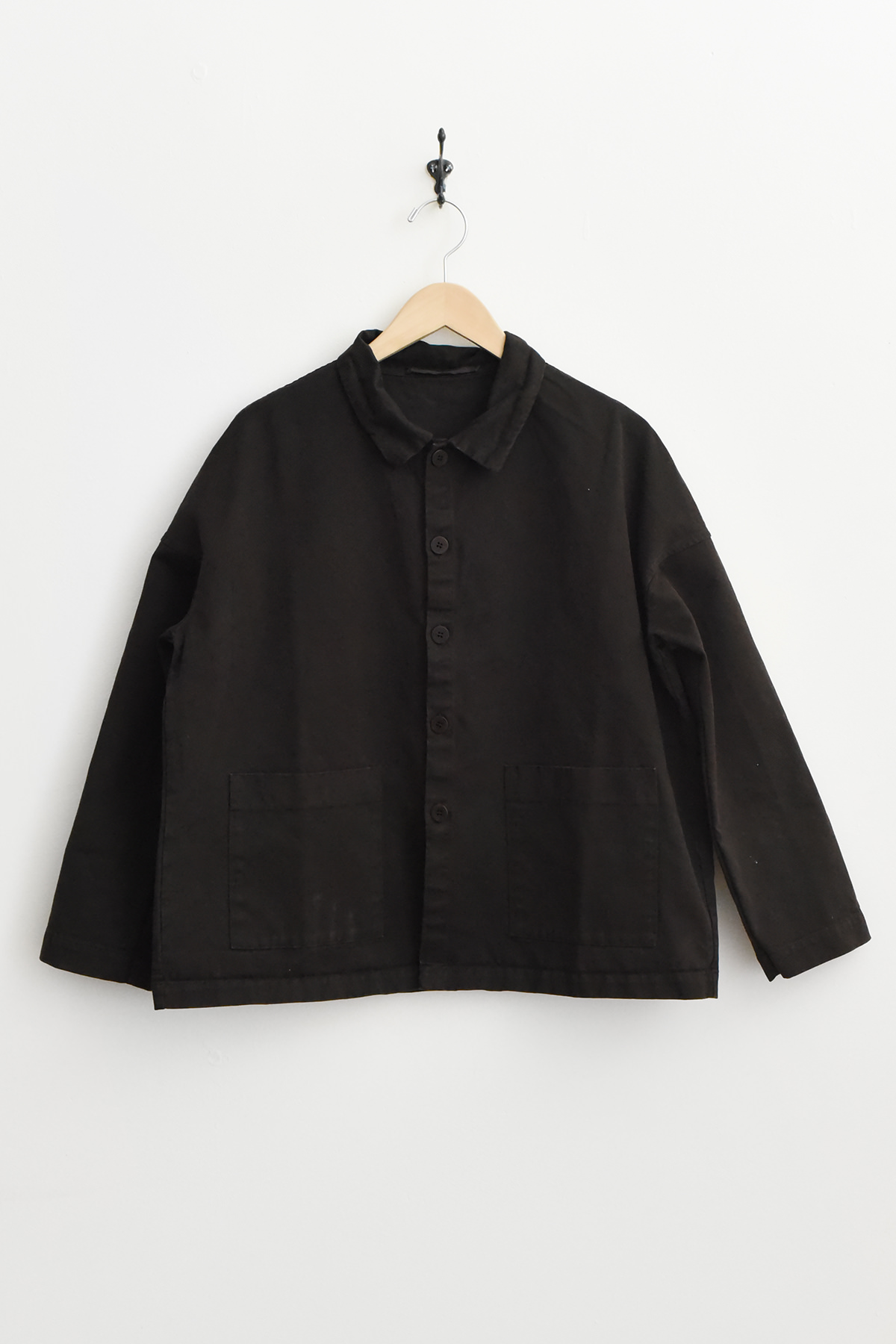 Album di Famiglia 4286 Overshirt WCC in Navy, featuring a button-up front, collar, and two front pockets, displayed on a wooden hanger against a white wall.
