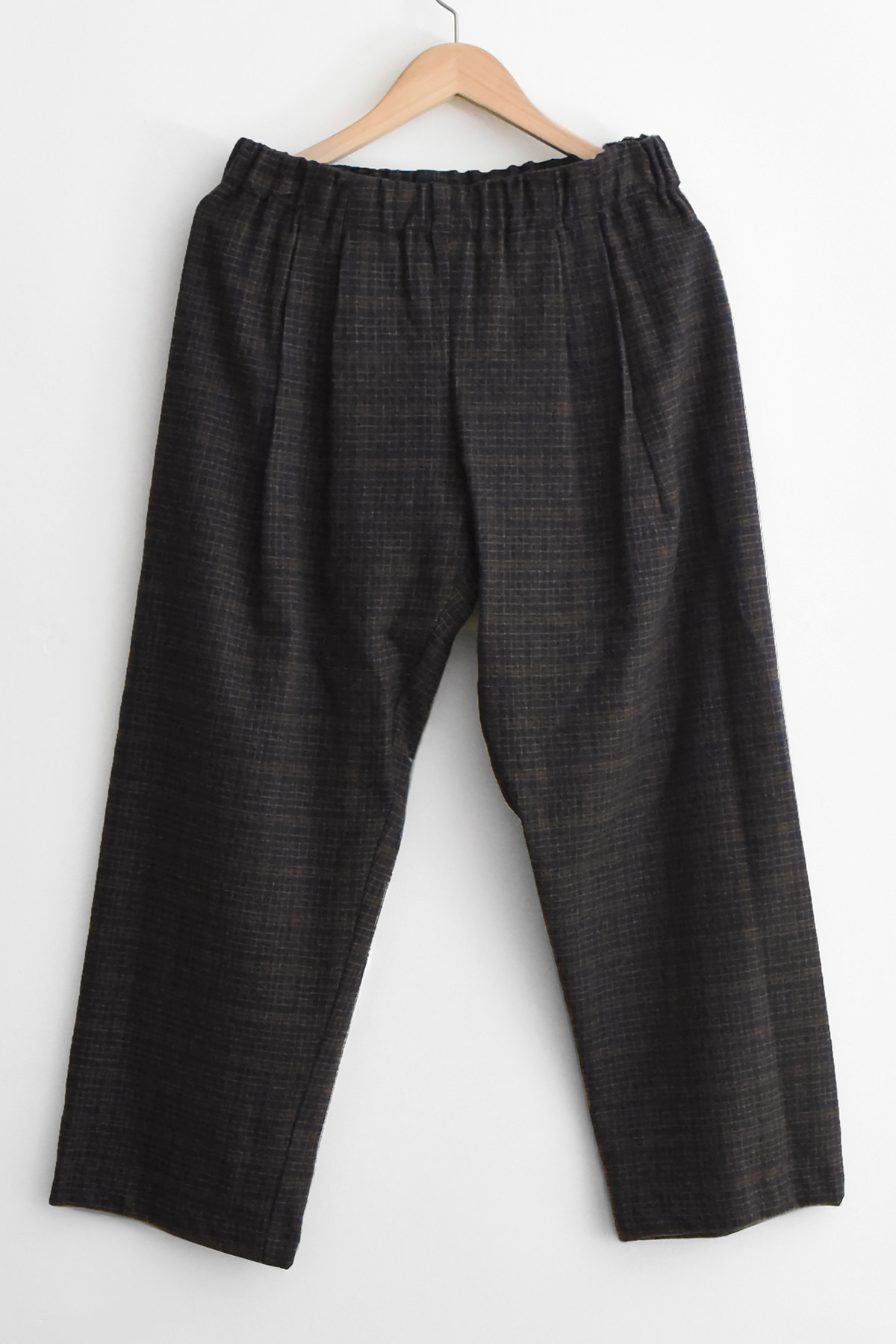 Apuntob (a.b) P1382 Trousers - Blue Mud, featuring dark blue fabric with a faint grid pattern and an elasticized waist, hanging on a wooden hanger.