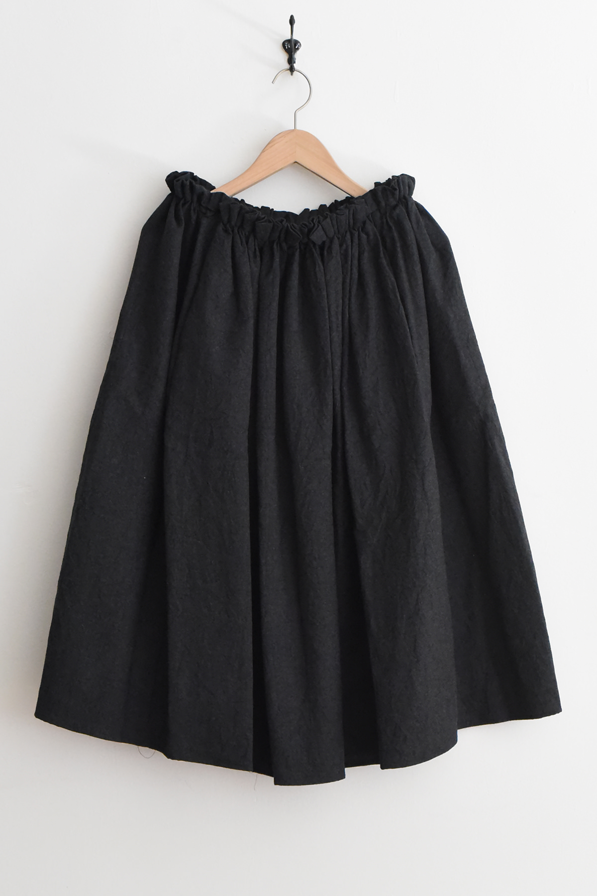 Apuntob (a.b) P2116 graphite gathered-waist skirt on a wooden hanger.