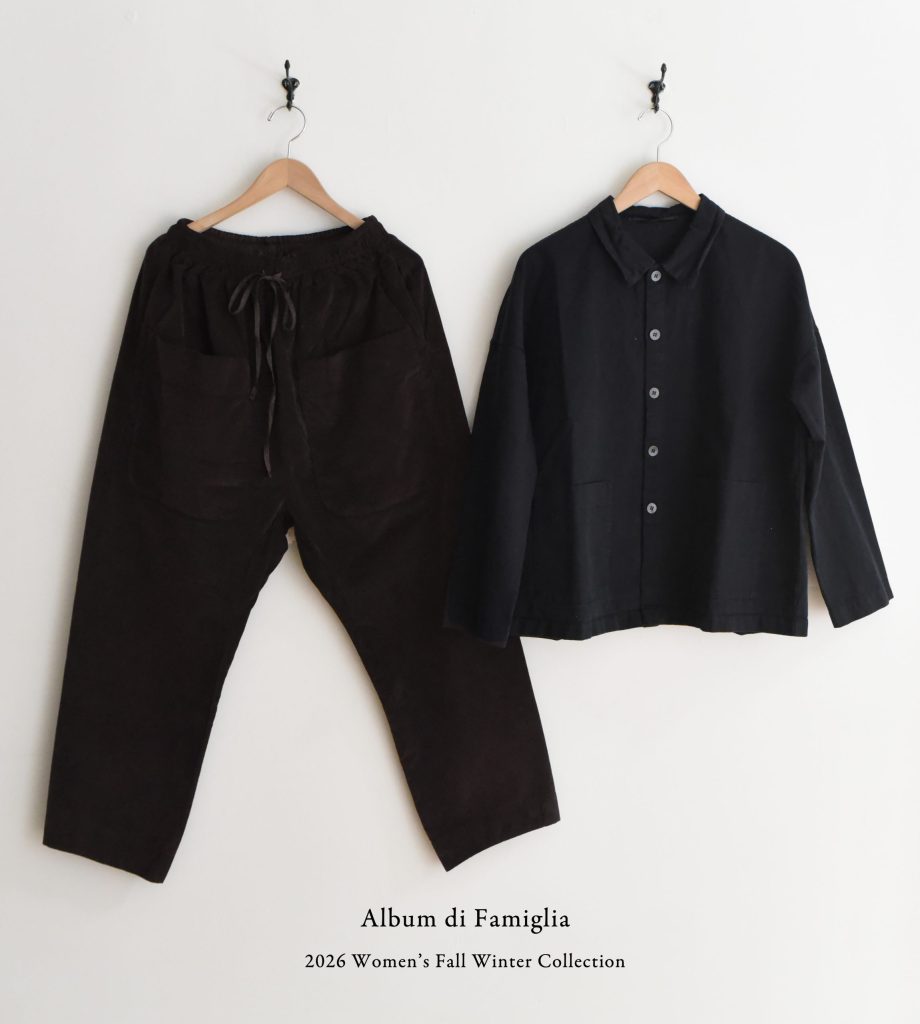 Black drawstring pants and a button-up shirt hanging on hooks, labeled Album di Famiglia 2026 Womens Fall Winter Collection.