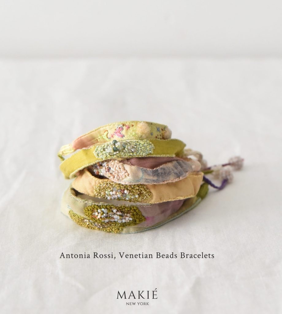 A stack of five fabric bracelets decorated with embroidery and beads, labeled Antonia Rossi, Venetian Beads Bracelets.