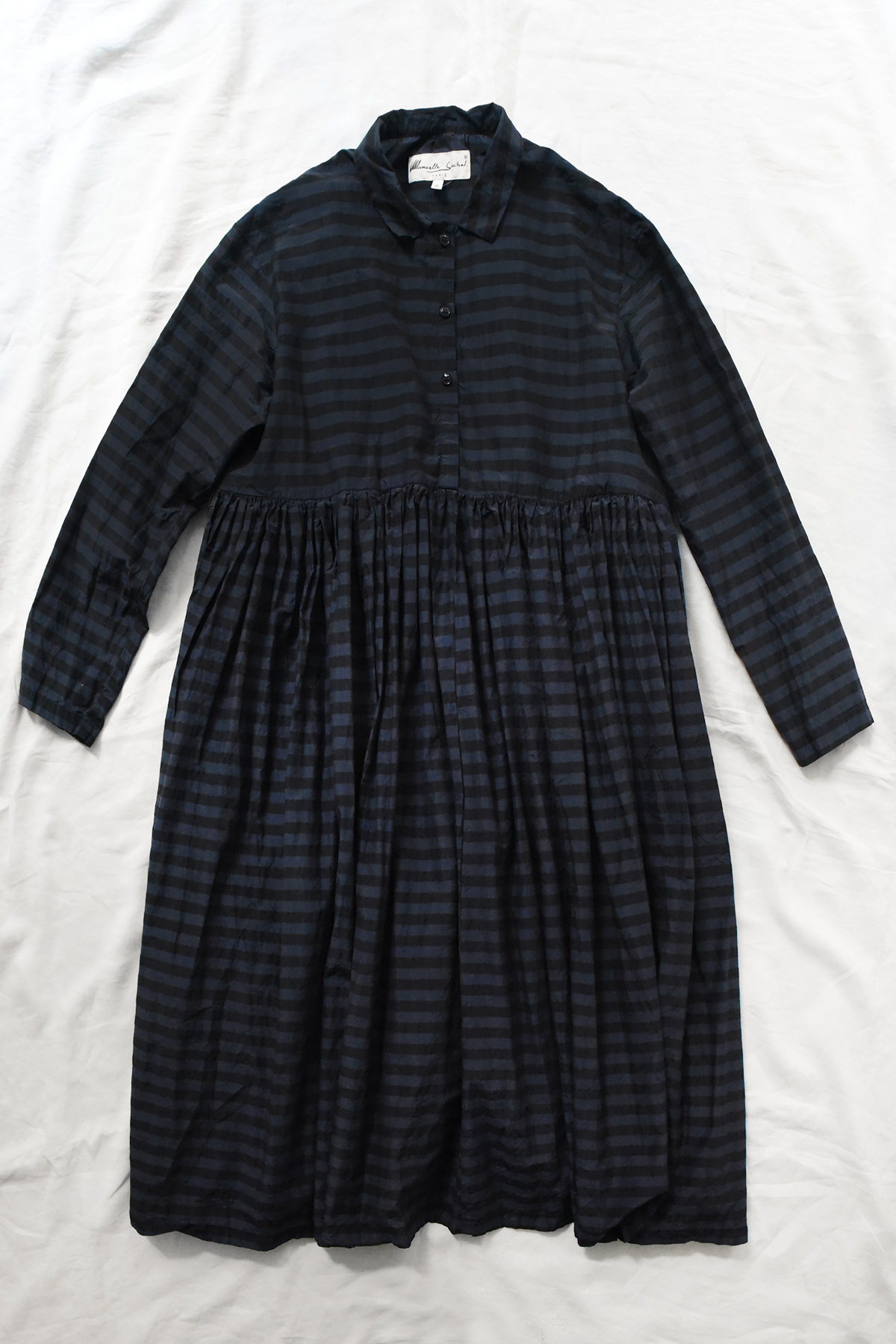 Manuelle Guibal, 7142 Shirt Dress YSH - Noctis, a long-sleeved, knee-length shirt dress in a dark blue and black horizontal stripe pattern, featuring a buttoned bodice and a gathered waist.